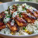 Smoky charred corn and crumbled cotija cheese top Street Corn Chicken and Rice Bowls drizzled with crema.