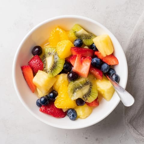 Colorful summer Fruit Salad is tossed in sweet orange glaze and served in a chilled glass bowl.