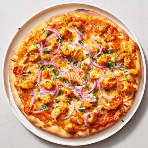 Sliced wedges of Chicken BBQ Pizza on a wooden board, showcasing juicy grilled chicken under a tangy barbecue sauce glaze.