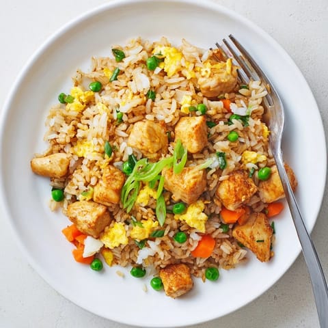 A large skillet of savory Chicken Fried Rice with scrambled eggs and vibrant mixed vegetables, ready to serve.