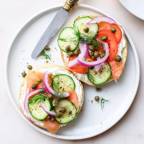 A toasted sesame bagel spread thick with cream cheese, topped with smoked salmon, capers, and thin red onion slices.