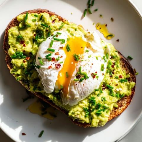 A close-up of vibrant avocado toast, garnished with fresh cilantro and a sprinkle of chili flakes.