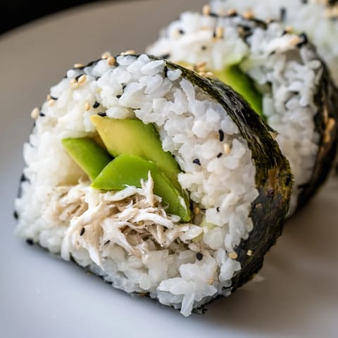 Sliced California Roll on a bamboo mat, creamy avocado and crab filling visible, garnished with sesame seeds for a fresh, homemade sushi look.
