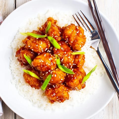 Crispy General Tsos Chicken bites glazed in sticky sauce over steamed rice.