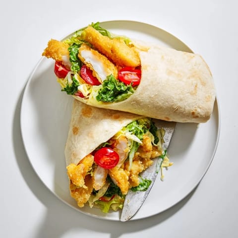 Sliced in half, this Hot Honey Chicken Caesar Wrap reveals layers of creamy Caesar salad, spicy glazed chicken, and optional croutons for added crunch.