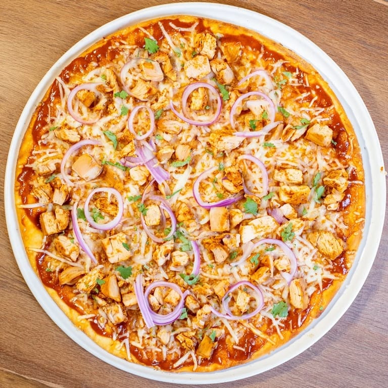 A rustic platter of Chicken BBQ Pizza garnished with fresh cilantro, paired with a crisp lager for a perfect meal.