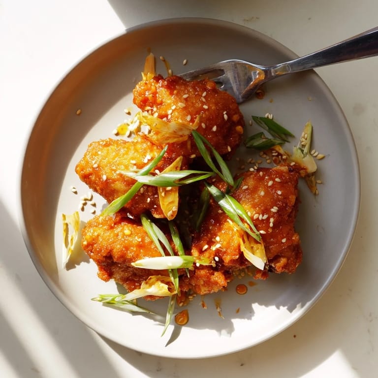Steaming Orange Chicken pieces in a wok with a glossy, tangy orange glaze and aromatics like garlic and ginger.