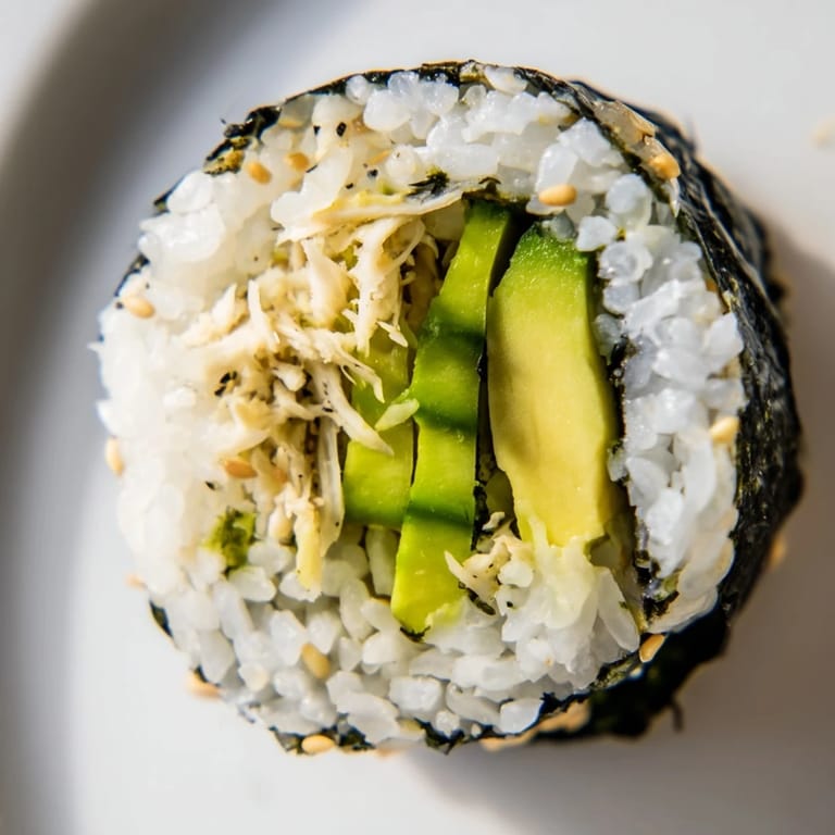 Glossy California Roll cross-section shows layered crab, avocado, and cucumber, wrapped in seasoned rice and nori for authentic texture.