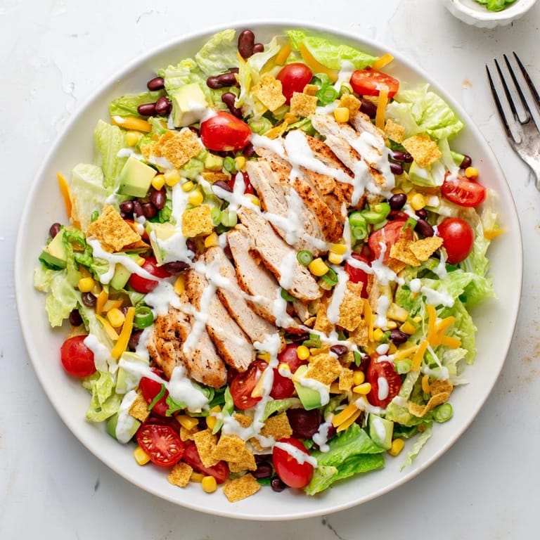 Zesty lime dressing drizzled over a vibrant bowl of Crunchy Taco Chicken Salad, ready to serve with extra shells for dipping.