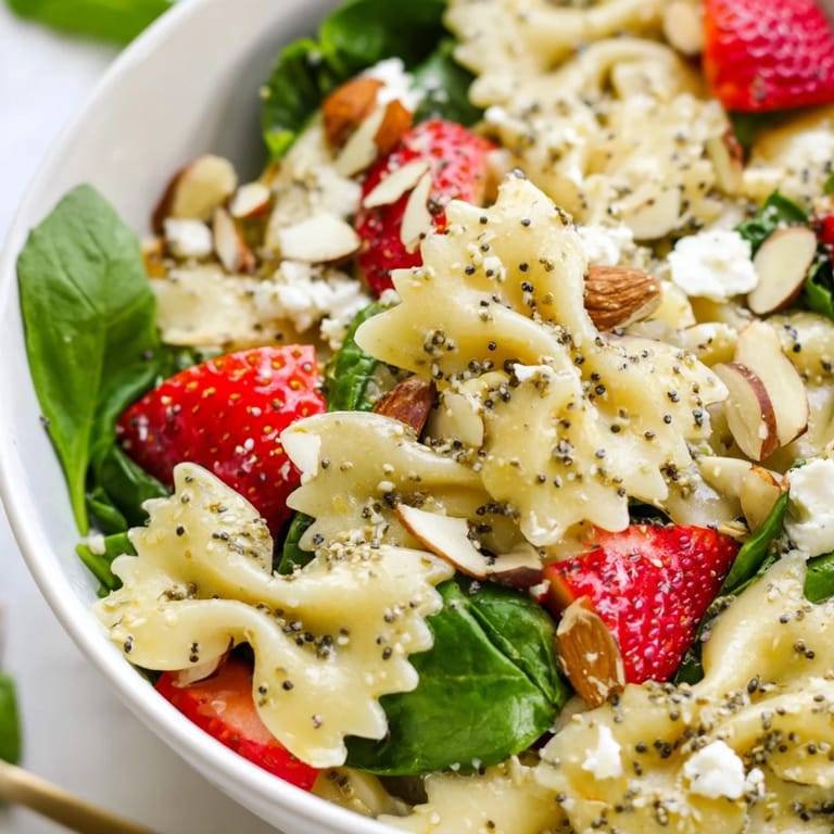 Bright Spring Spinach Strawberry Pasta Salad on a rustic table, featuring sweet berries, tender pasta, and herbs with a light drizzle.