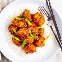Crispy General Tsos Chicken bites glazed in sticky sauce over steamed rice.