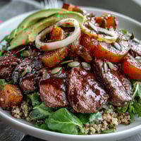 Golden roasted butternut squash steak bowls feature fluffy quinoa, smoky steak, and creamy avocado on a bed of vibrant greens.